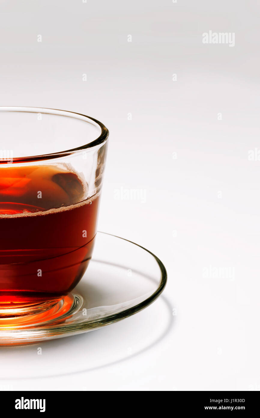 transparent glass cup with tea on a saucer on a white background Stock Photo