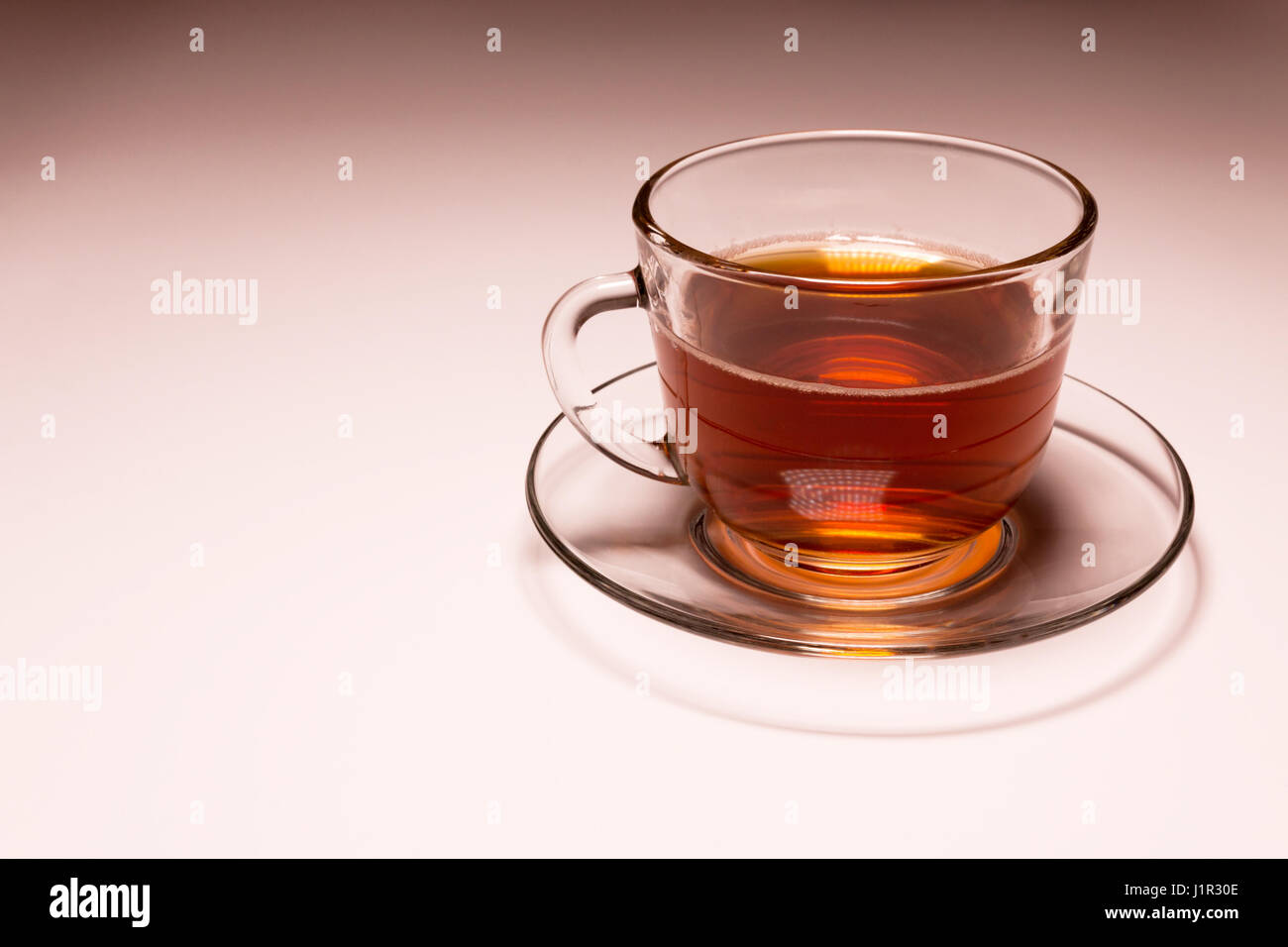 transparent glass cup with tea on a glass saucer Stock Photo