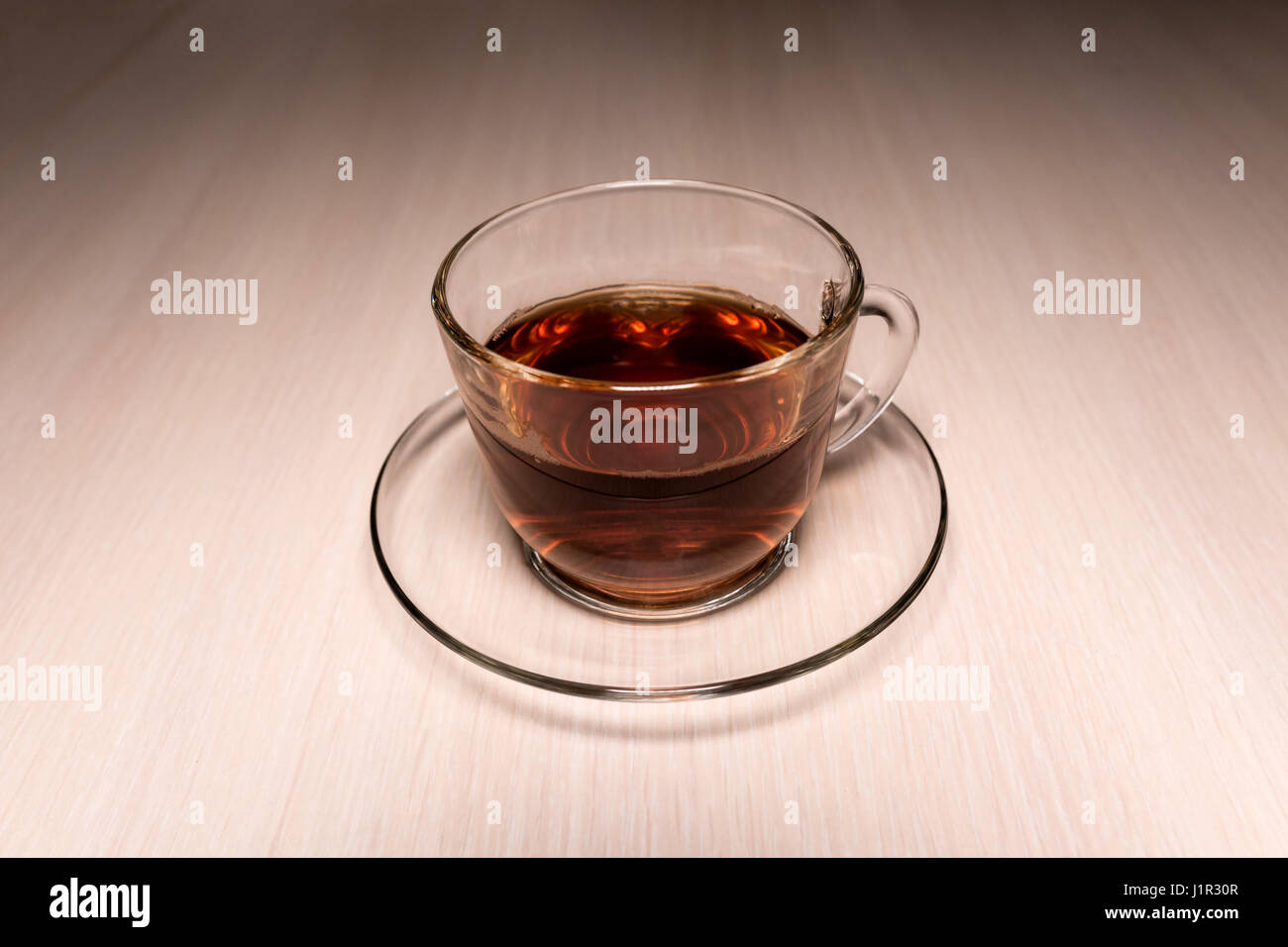 transparent glass cup with tea on a saucer placed on a table Stock Photo