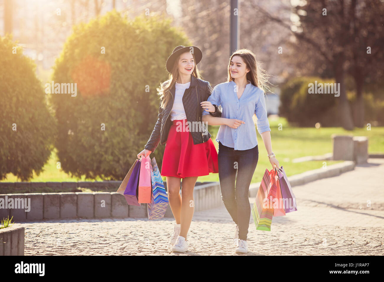 Two girls walking with shopping on city streets Stock Photo - Alamy