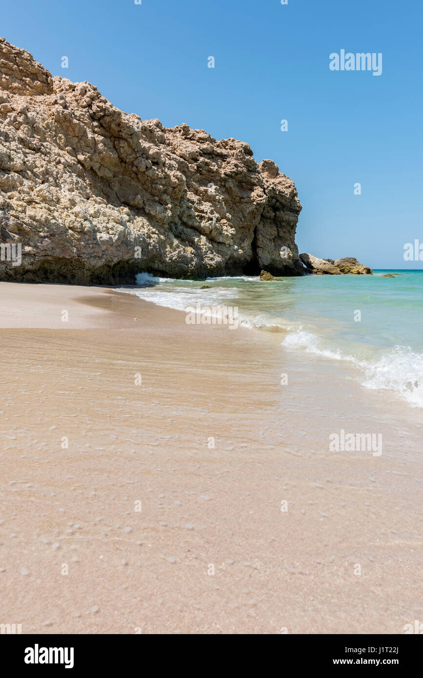 Vertical shot of Cliff and Wild beach at the coast with calm ocean of Ras Al Jinz, Sultanate of Oman. Copy space on the sand of the beach Stock Photo