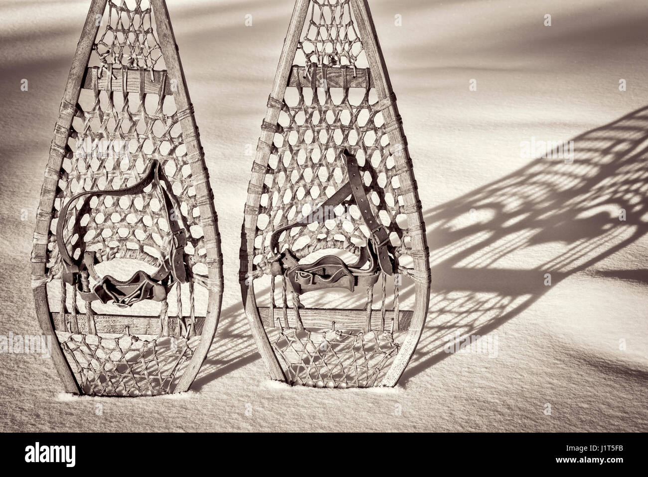 vintage wooden Huron snowshoes with leather binding in snow with shadow, retro sepia toning Stock Photo