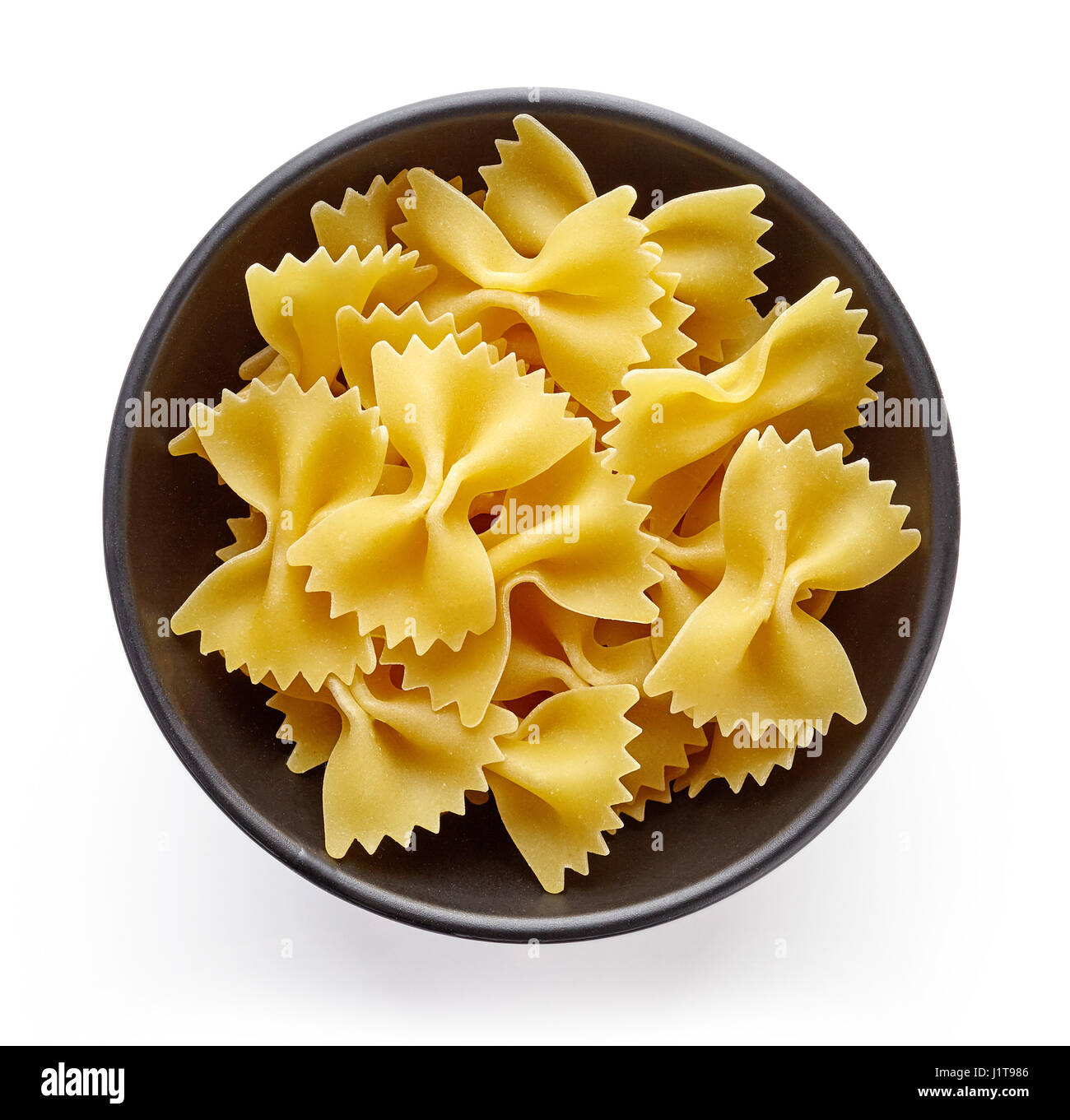 bow tie pasta in bowl, isolated on white background, top view Stock