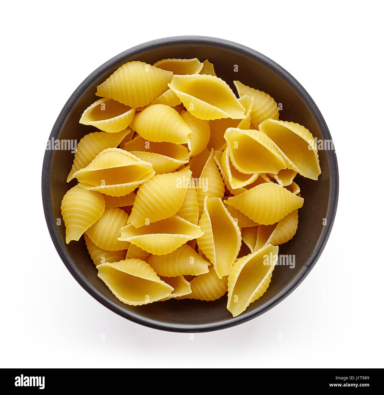 shell pasta in bowl, isolated on white background, top view Stock Photo