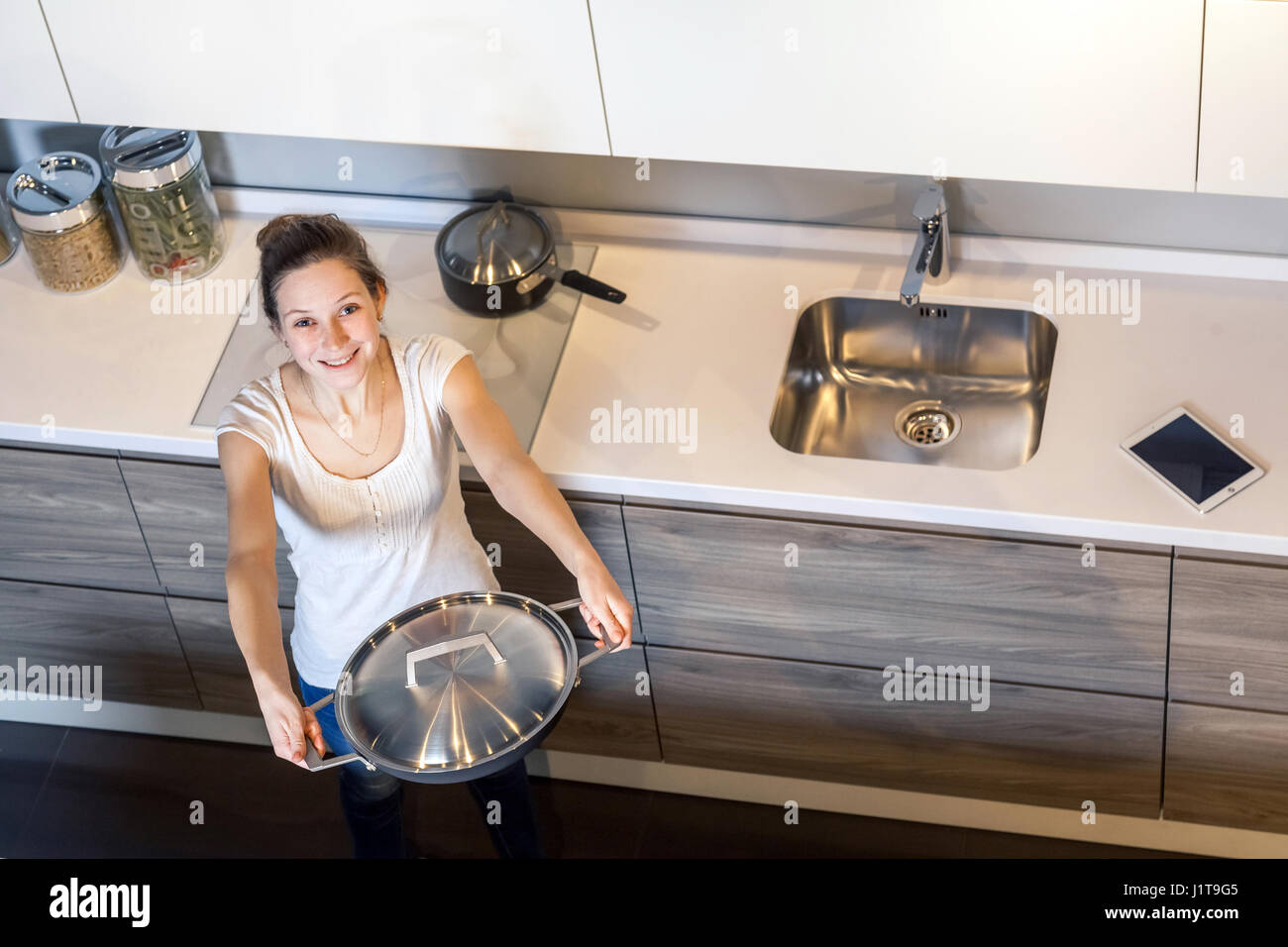 Happy beautiful woman with toothy smile holding kitchen pan and sharing. looking at camera. top view. Stock Photo