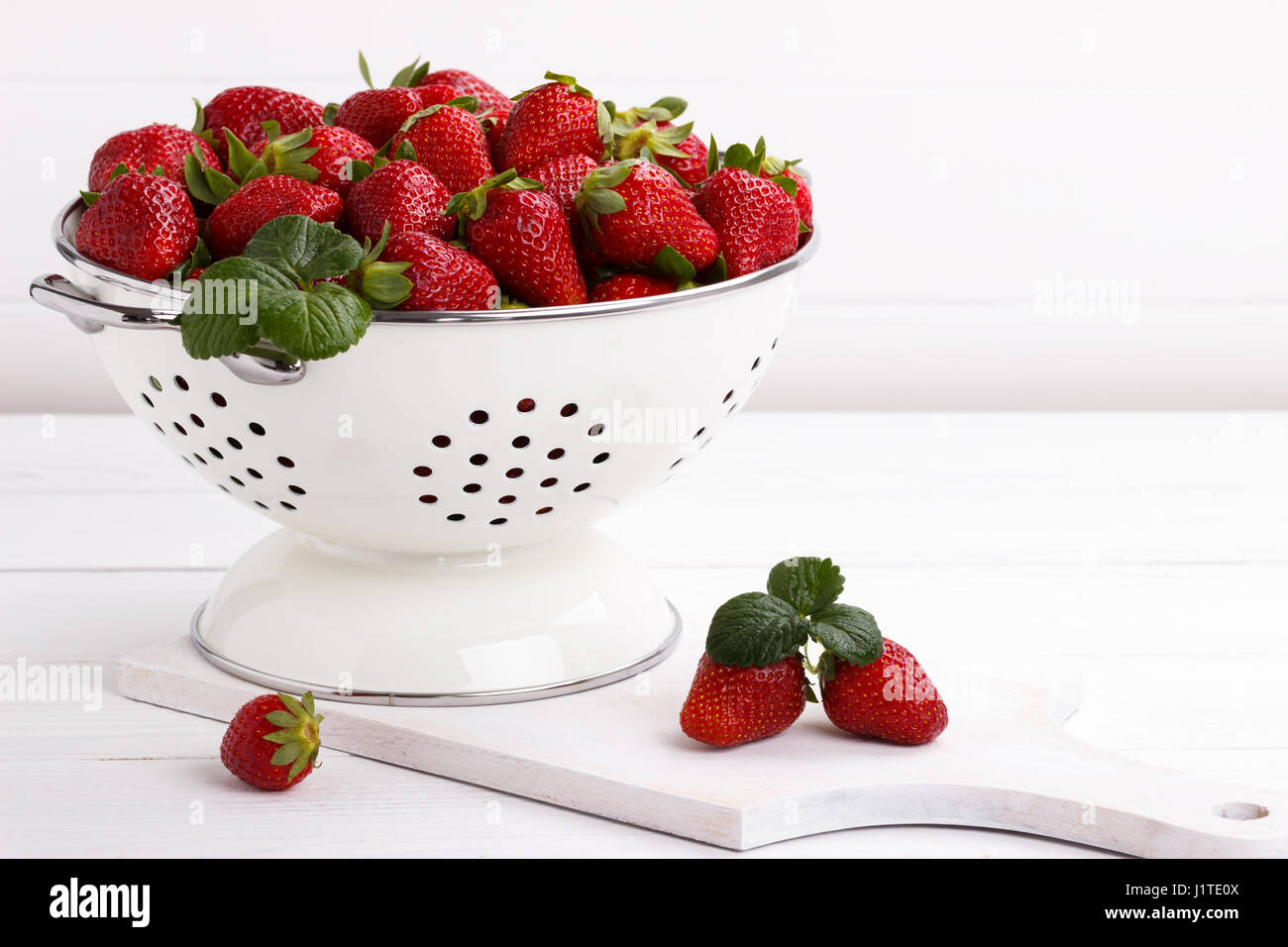 Fresh rip strawberries in a bowl on white wooden table Stock Photo - Alamy