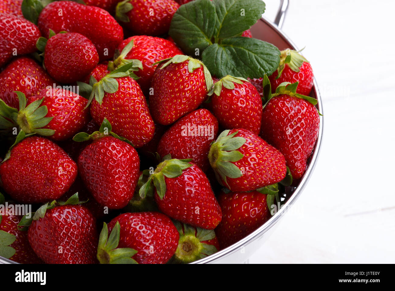 Fresh rip strawberries in a bowl on white wooden table Stock Photo - Alamy