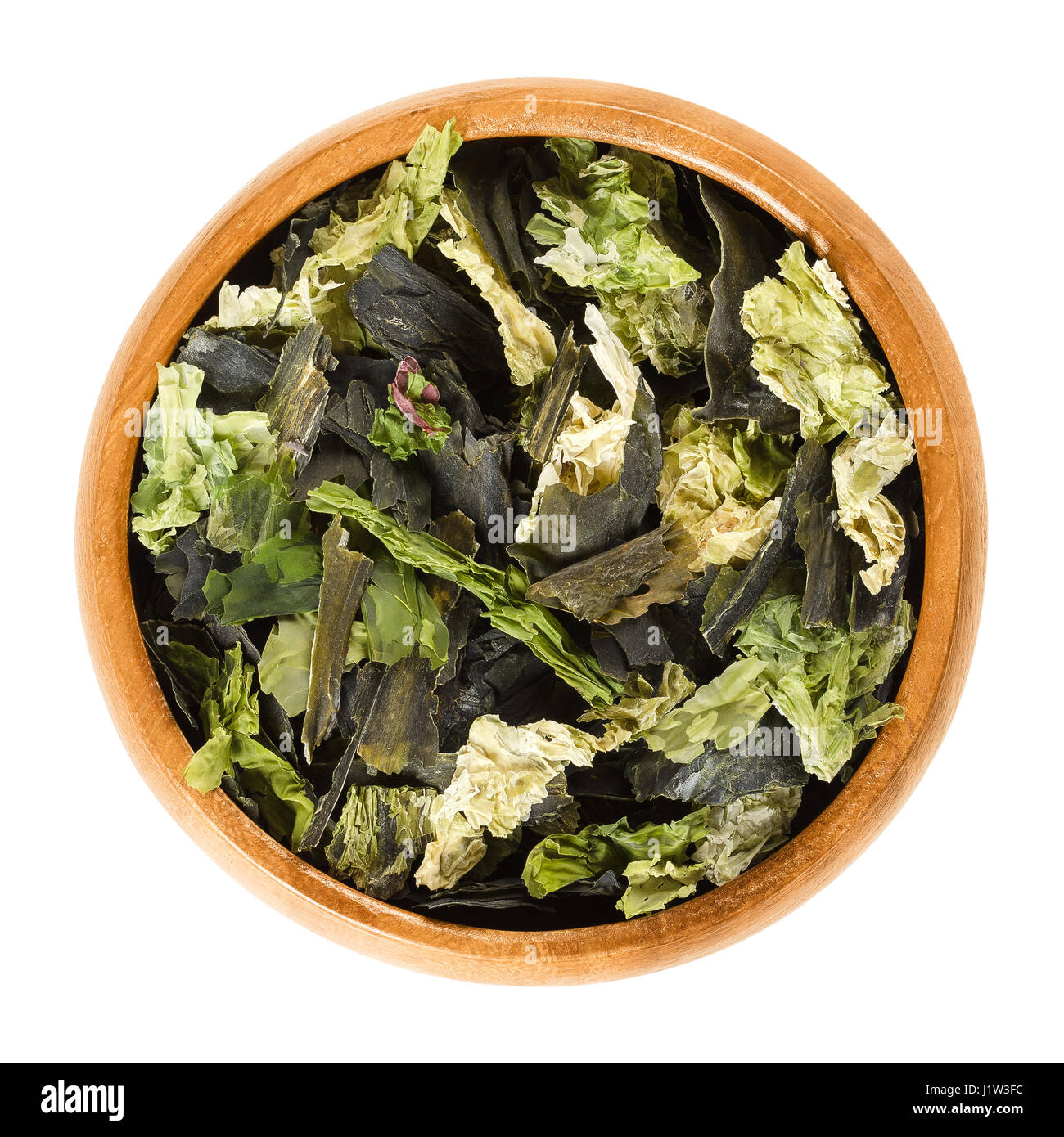 Dried algae flakes in wooden bowl. Mix of sea lettuce, wakame and nori. Edible green algae and seaweed. Ulva lactuca, Undaria pinnatifida. Stock Photo