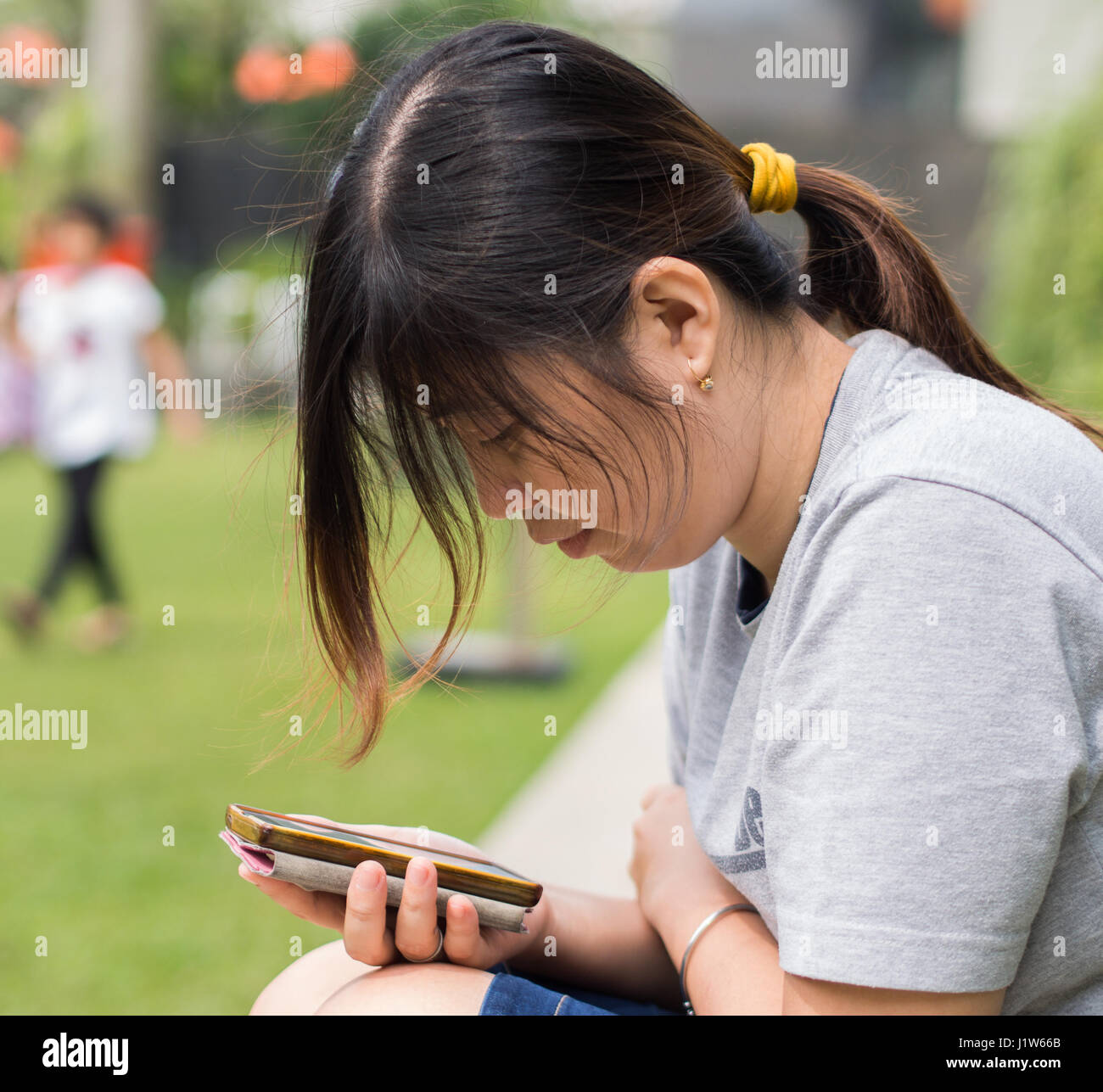 Woman using phone on park Stock Photo