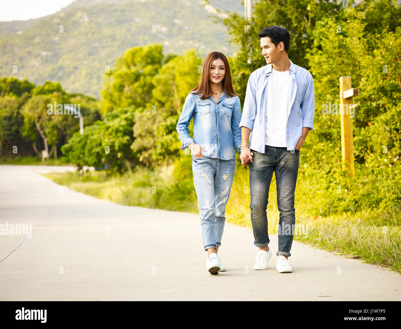 young asian couple walking on rural road. Stock Photo
