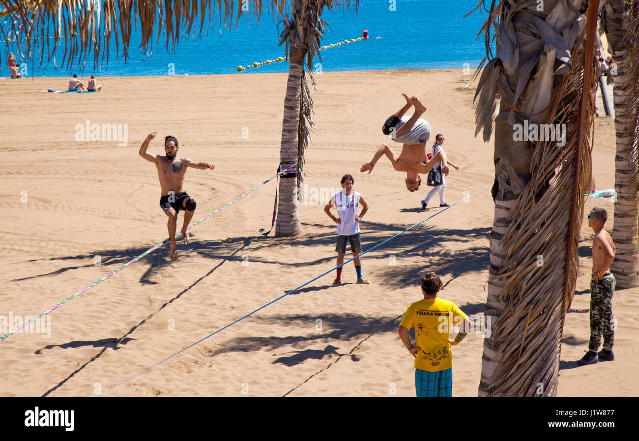 LAS PALMAS - April 15: A group pf young men practicing slacklining on Playa de Las Alcaravaneras beach, April 15, 2016 in Las Palmas, Gran Canaria, Sp Stock Photo