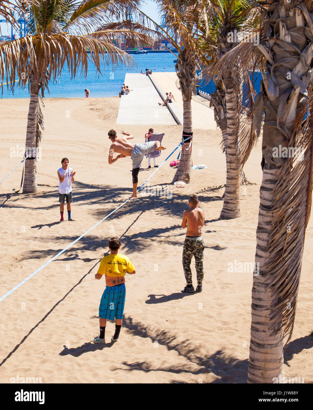 LAS PALMAS - April 15: A group of young men practicing slacklining on Playa de Las Alcaravaneras beach, April 15, 2016 in Las Palmas, Gran Canaria, Sp Stock Photo