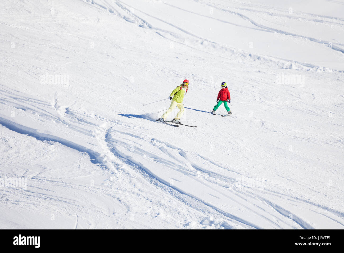 Active family, woman and boy in skiing suits, hitting the slope at snowy mountains Stock Photo