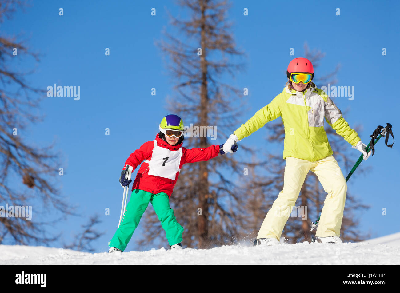 Portrait of active family skiing holding hands at sunny snowy day Stock Photo