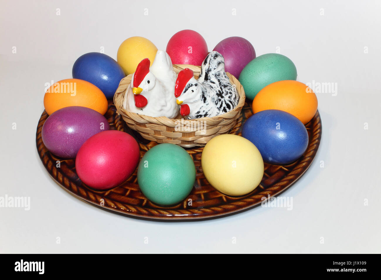 bunte Ostereier in einem Keramik-Teller mit Porzellanhühnern als Salz-und Pfefferstreuer; colored Easter eggs on a ceramic egg plate Stock Photo