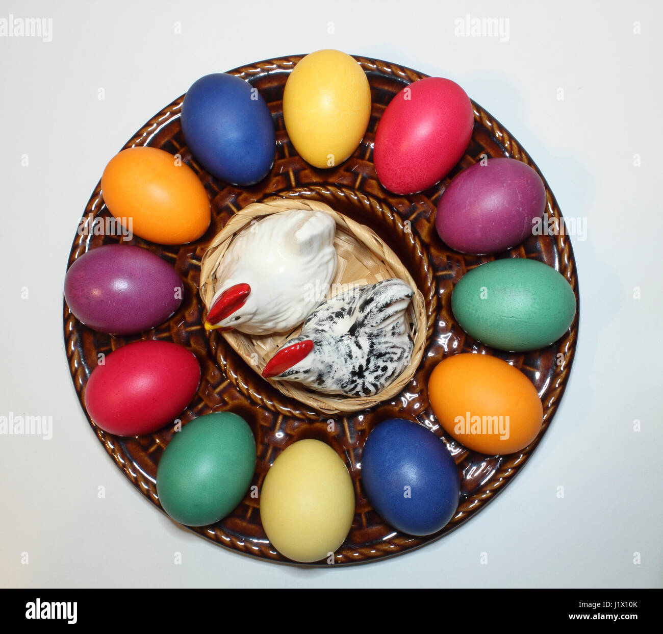 bunte Ostereier in einem Keramik-Teller mit Porzellanhühnern als Salz-und Pfefferstreuer; colored Easter eggs on a ceramic egg plate Stock Photo