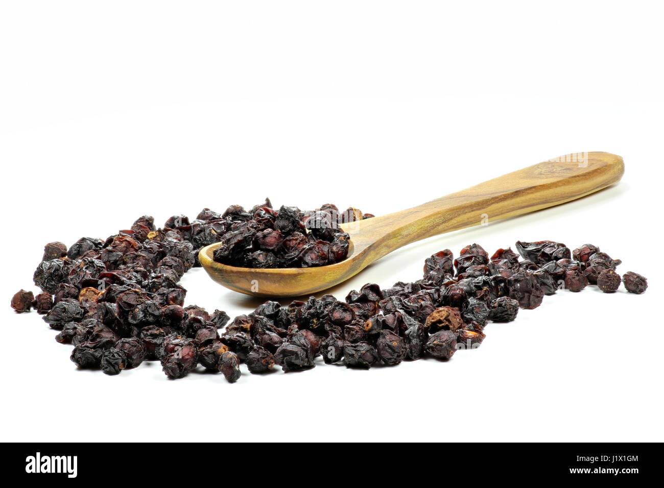 dried schisandra berries with a spoon made of olivewood isolated on