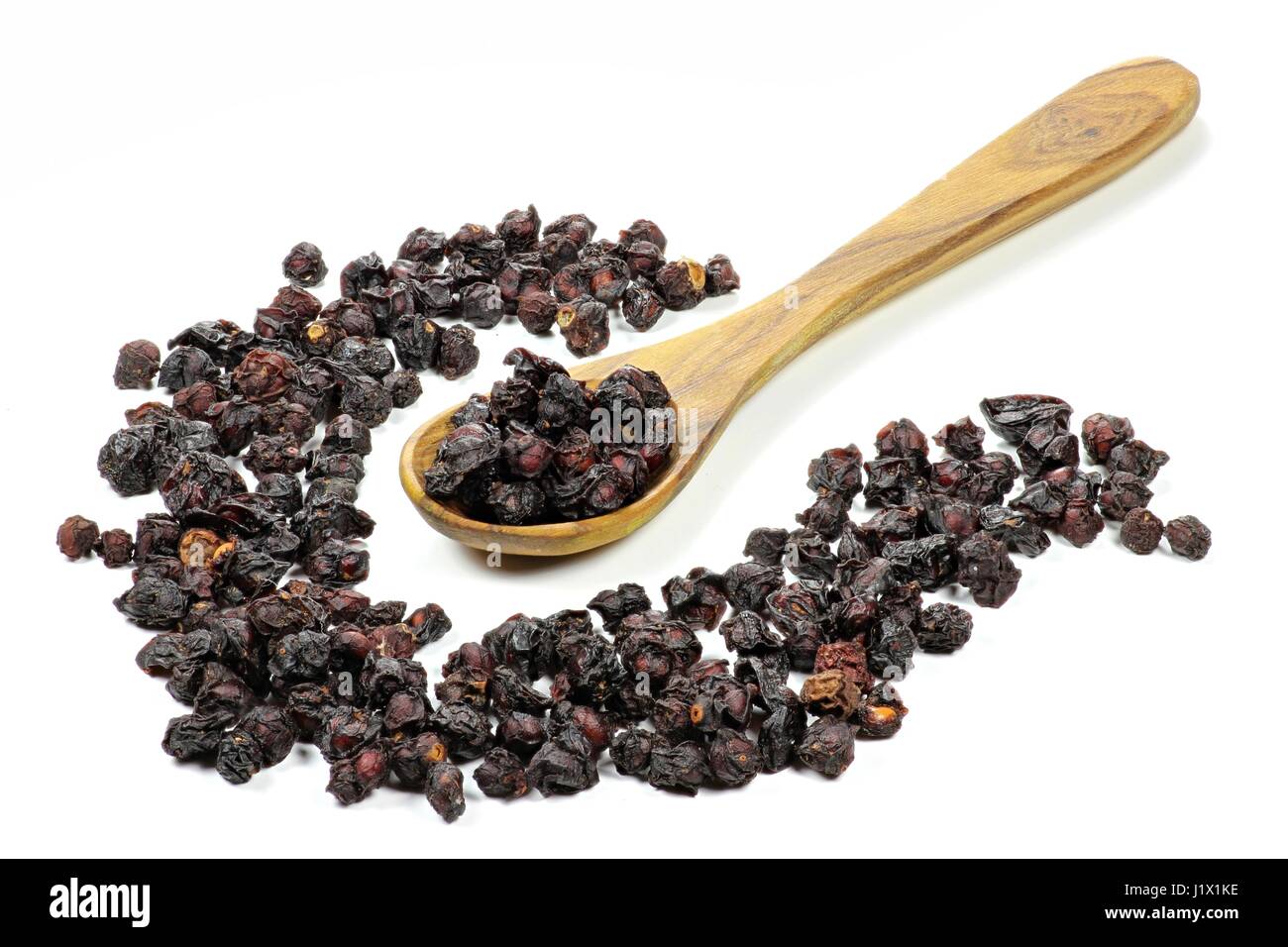 dried schisandra berries with a spoon made of olivewood isolated ...