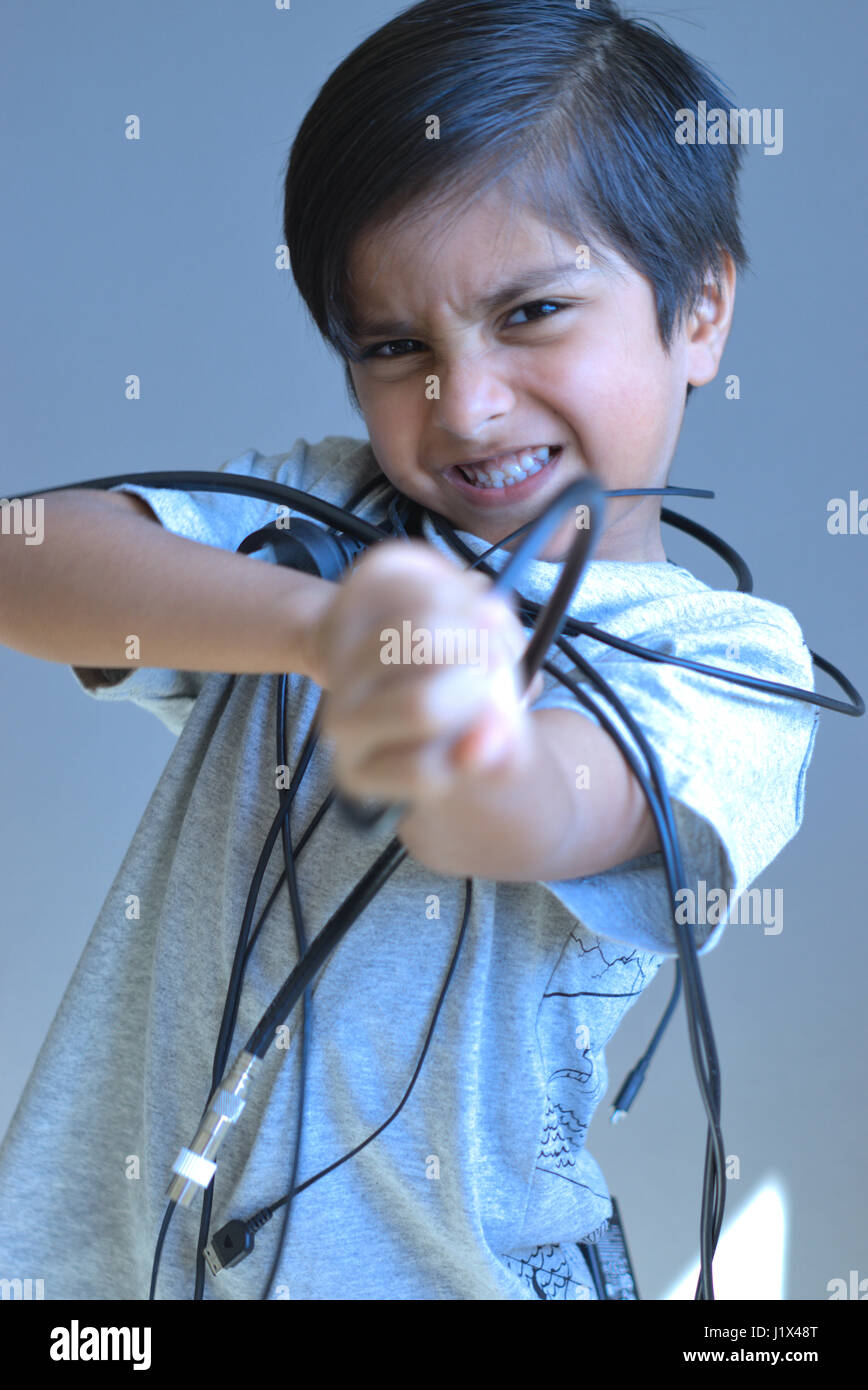 Little Furious kid tangled in wires. Frustrated Kid trying to break free. Stock Photo