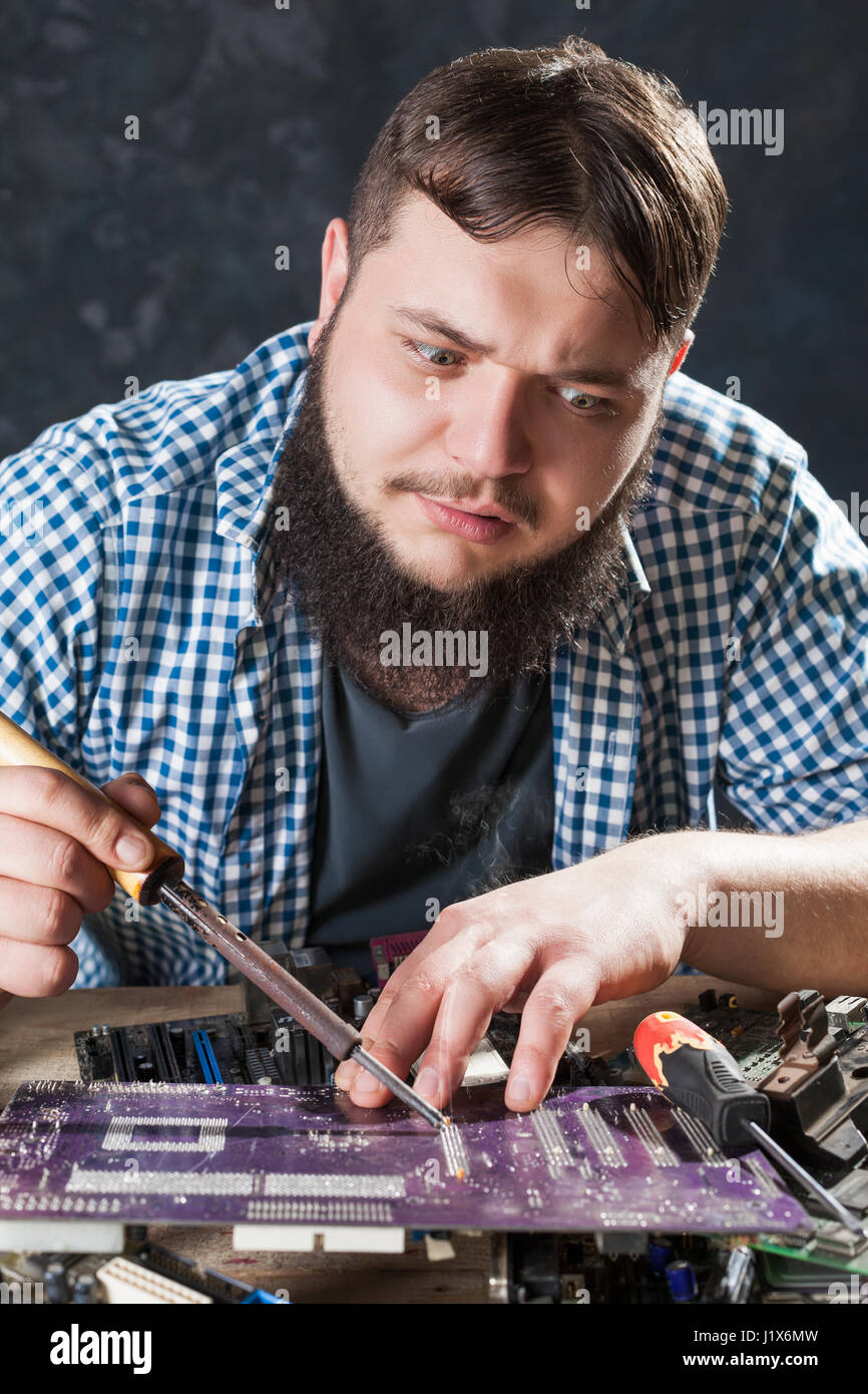 Repairman fixing problem with soldering tool. Engineer repairs computer
