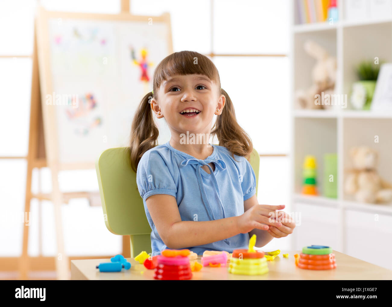 Child playing plasticine in kindergarten. Stock Photo