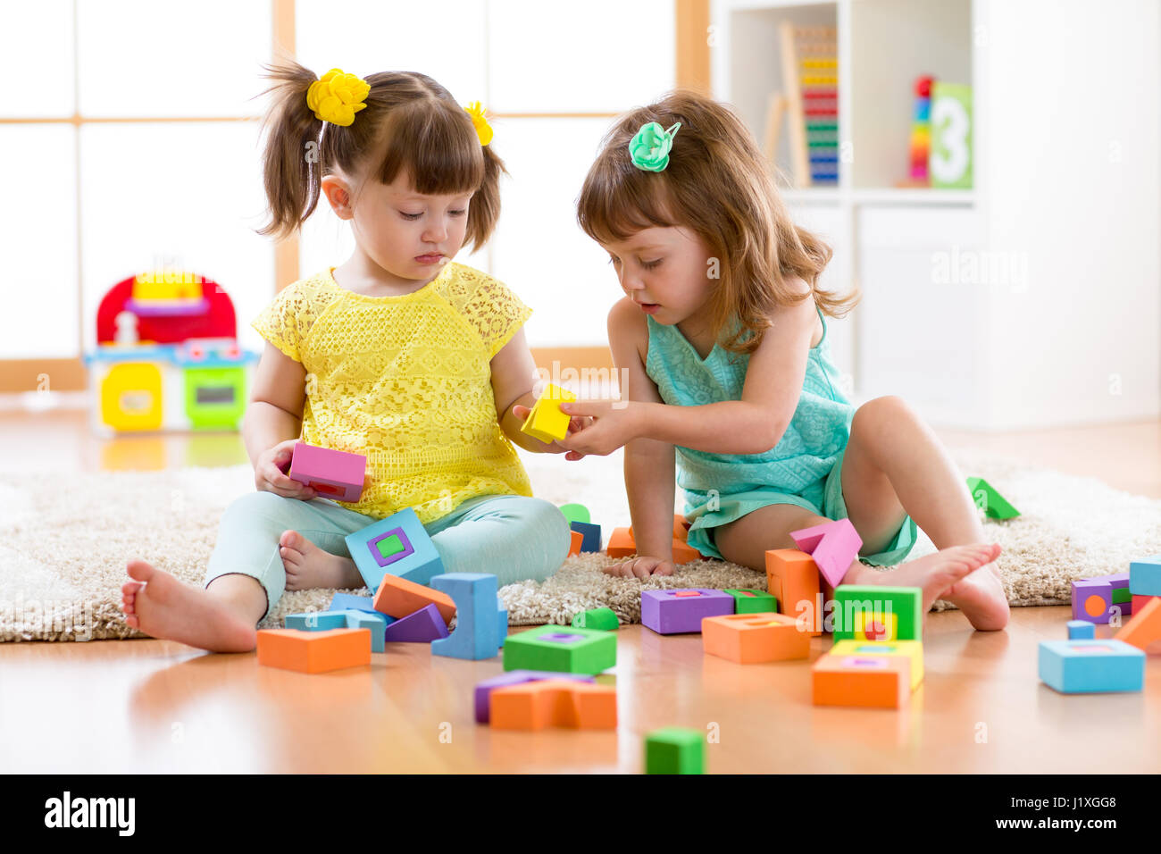 Two friends kids play together in kindergarten, daycare or home Stock Photo