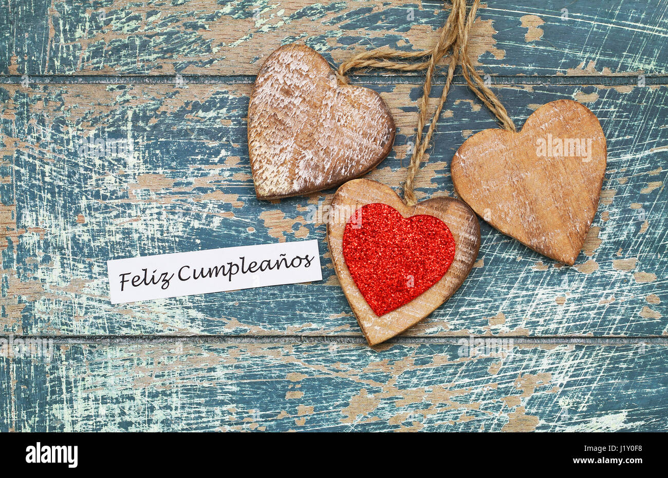 Feliz Cumpleanos (Happy Birthday in Spanish) with three wooden hearts Stock Photo
