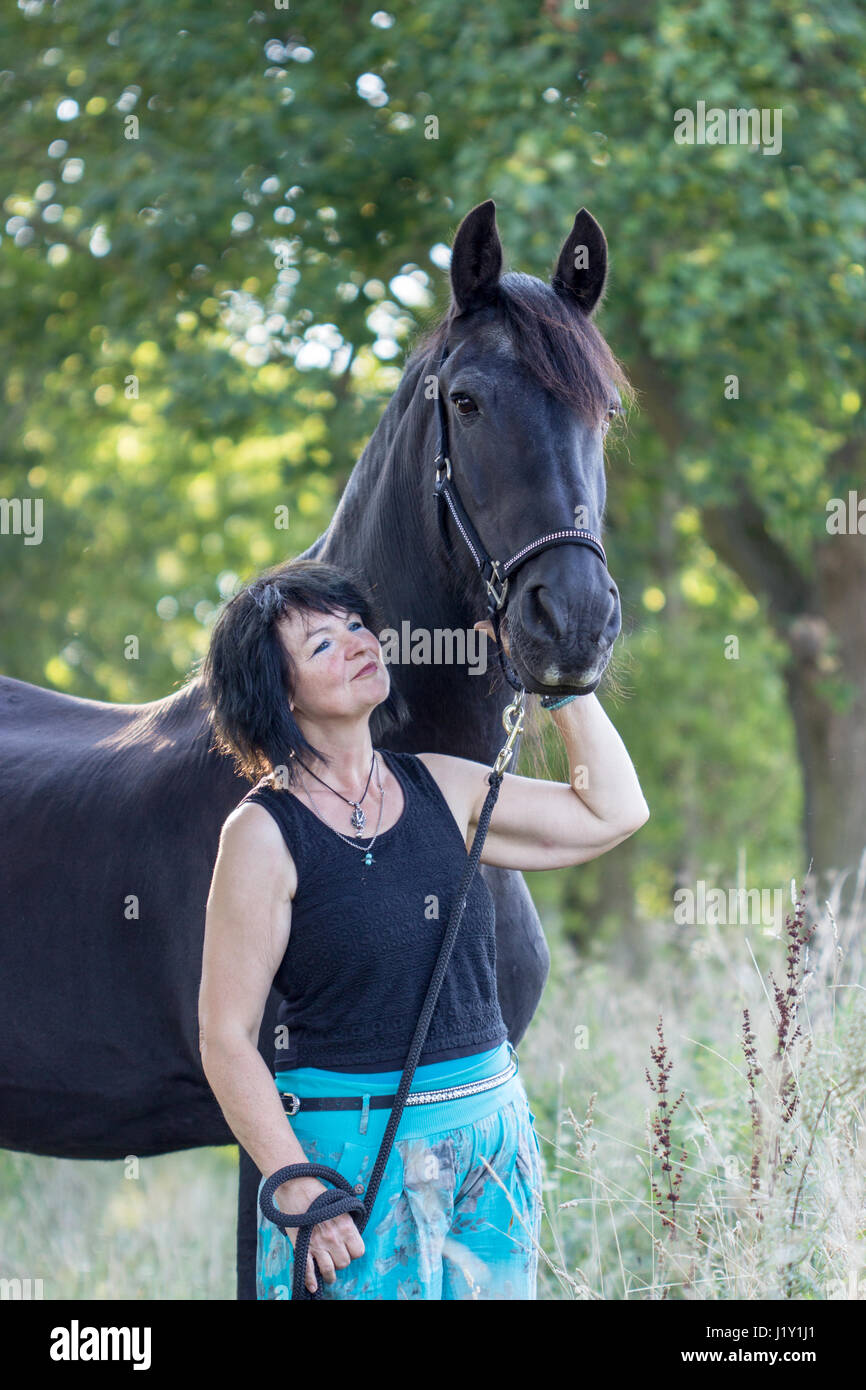 Brunette woman with black horse in forest Stock Photo