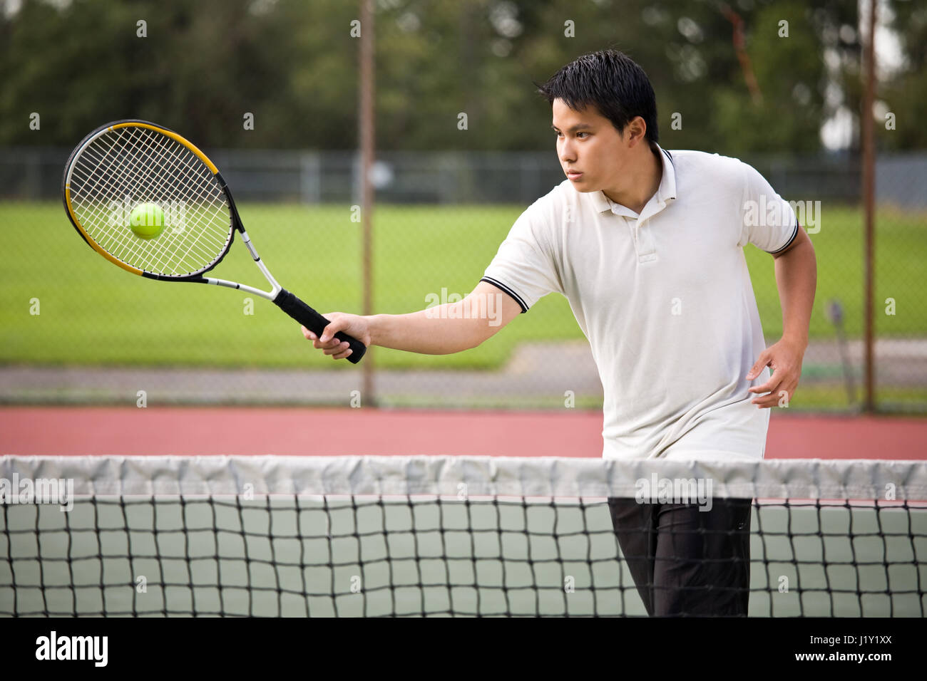 An asian tennis player hitting the ball Stock Photo