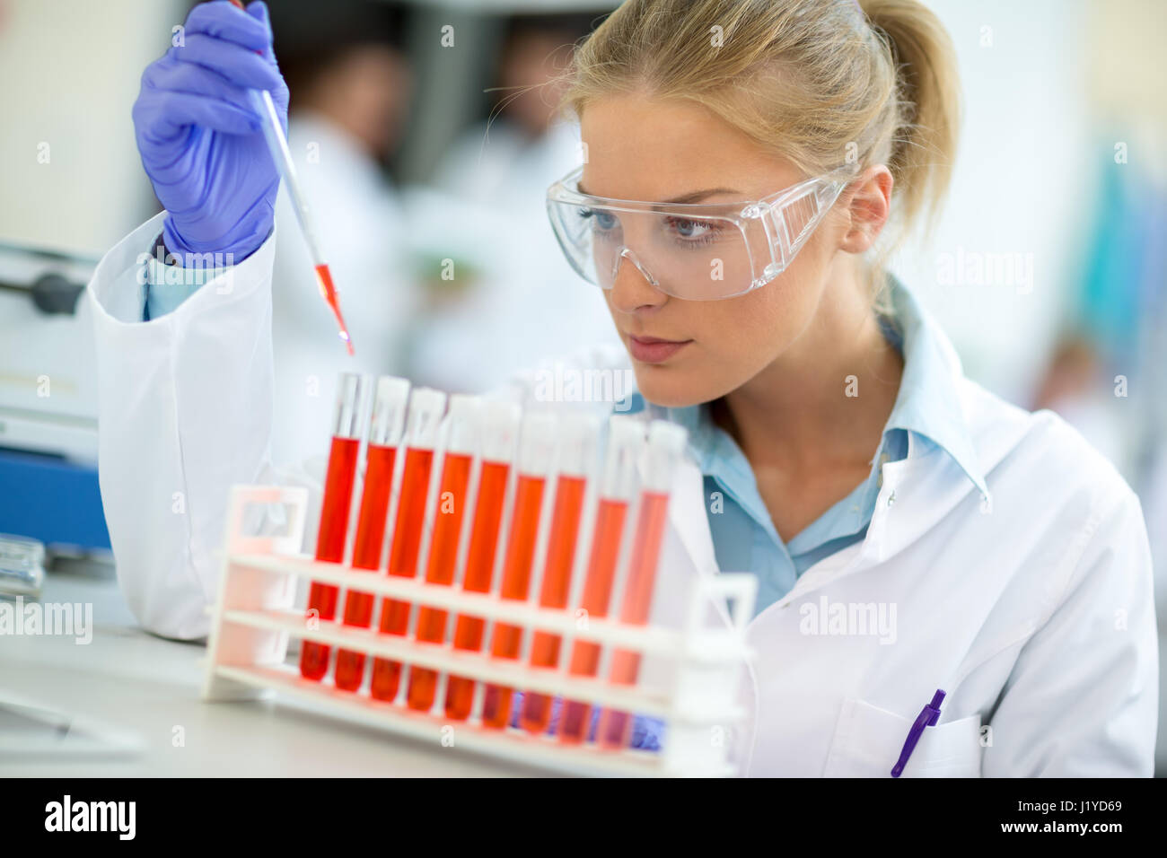 Young attractive chemical assistant work with test tubes in chemical laboratory Stock Photo