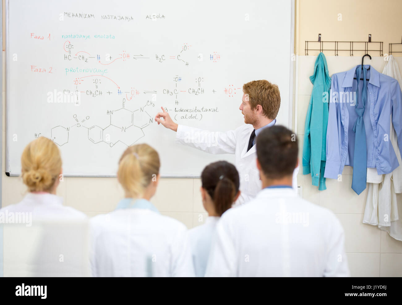 Young male chemical teacher explain lesson to his students in front of ...