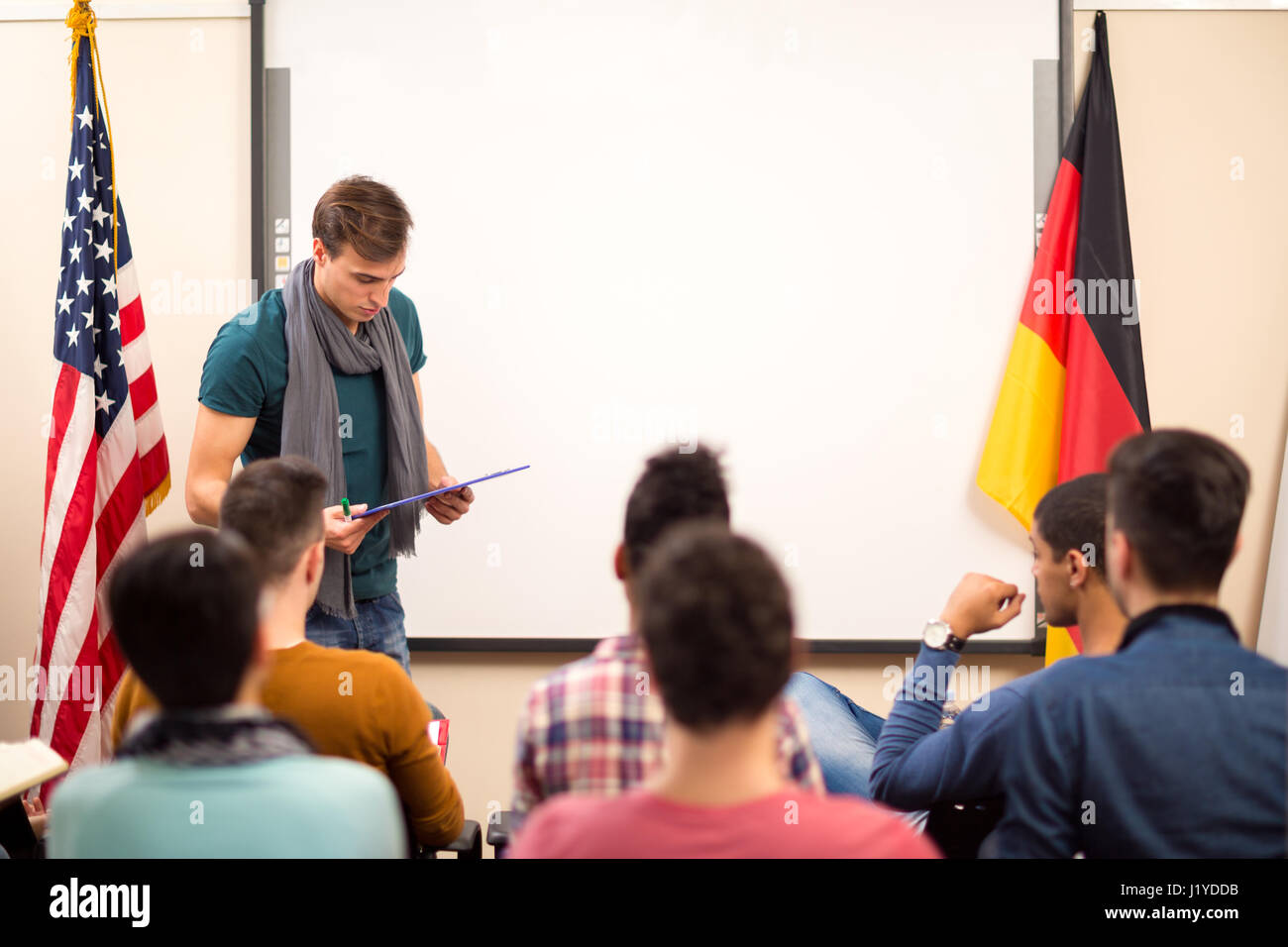 Handsome assistant looks in his lecture material and read to students Stock Photo