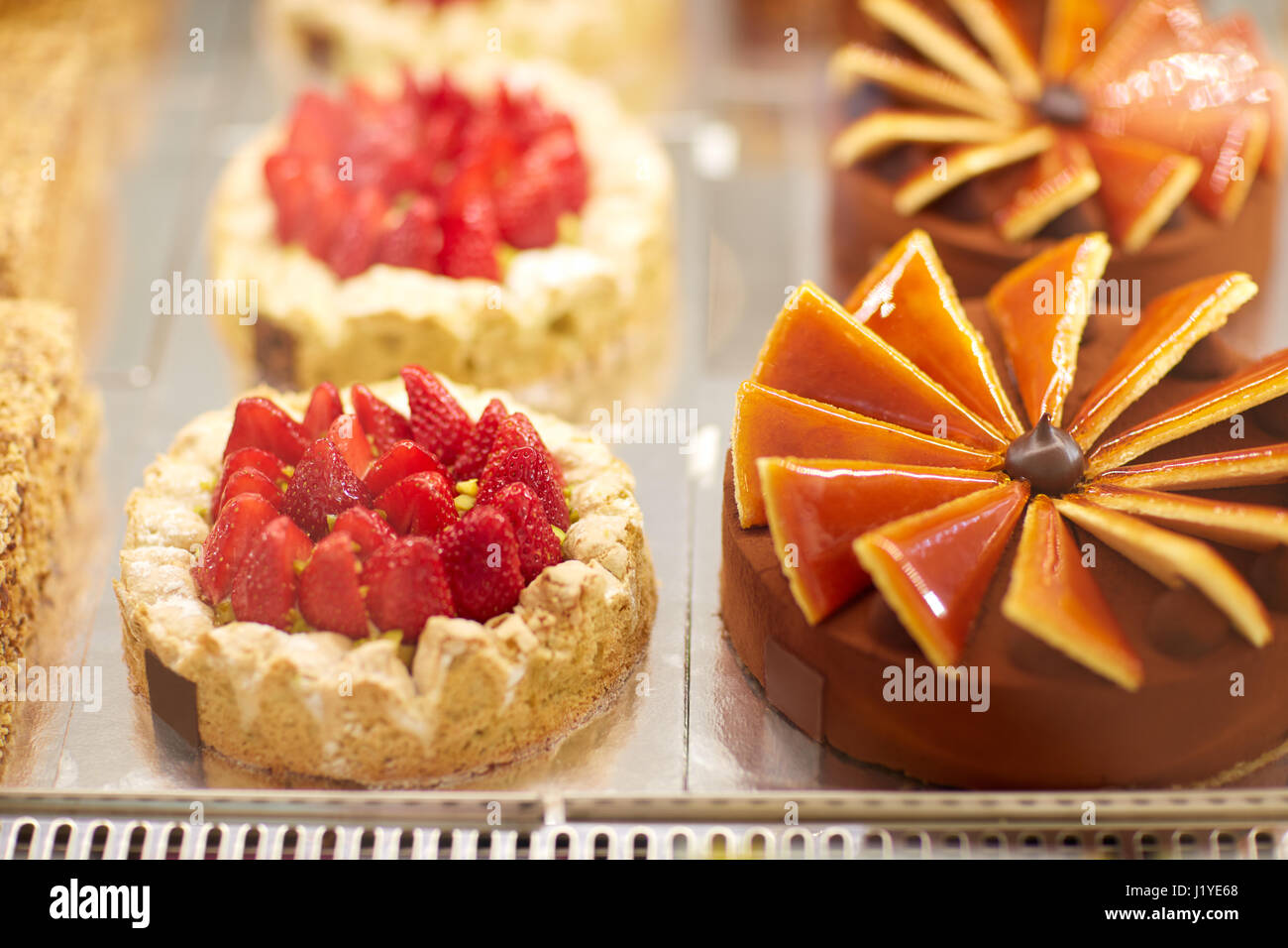 Different beautiful and tasty cakes in display case in pastry shop