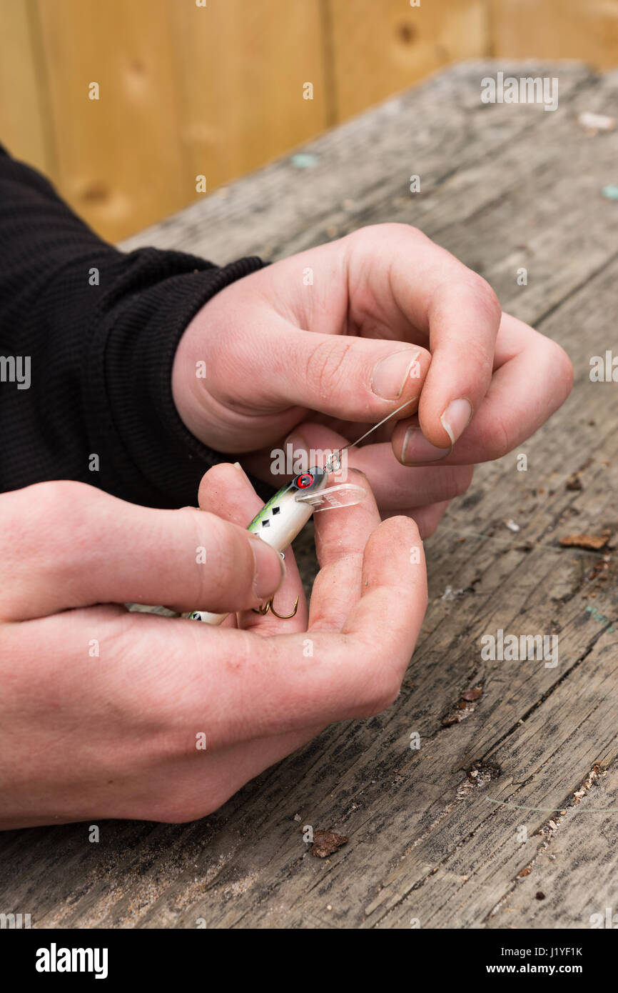 male hands tying a fishing lure to monofilament line Stock Photo Alamy