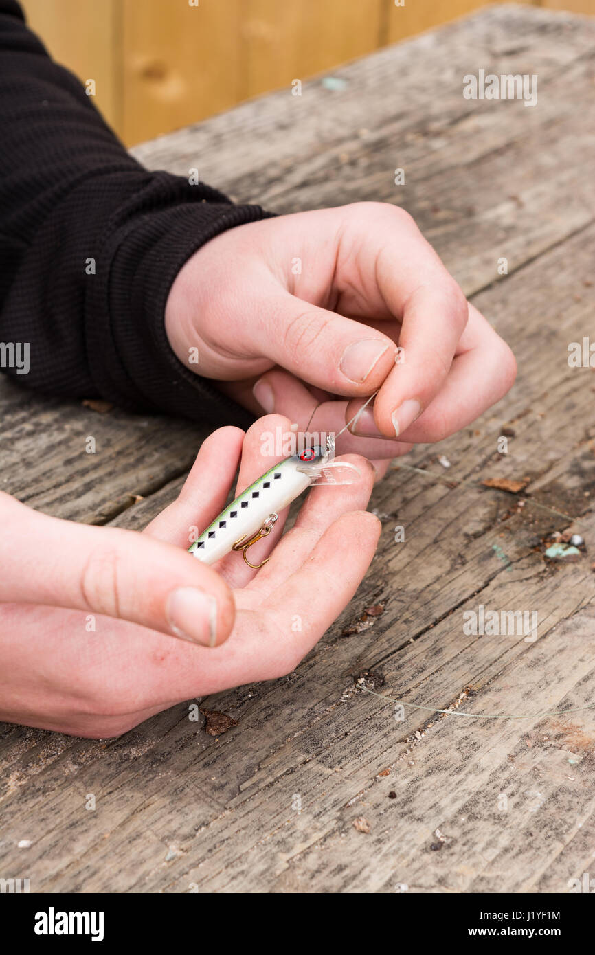 male hands tying a fishing lure to monofilament line Stock Photo Alamy