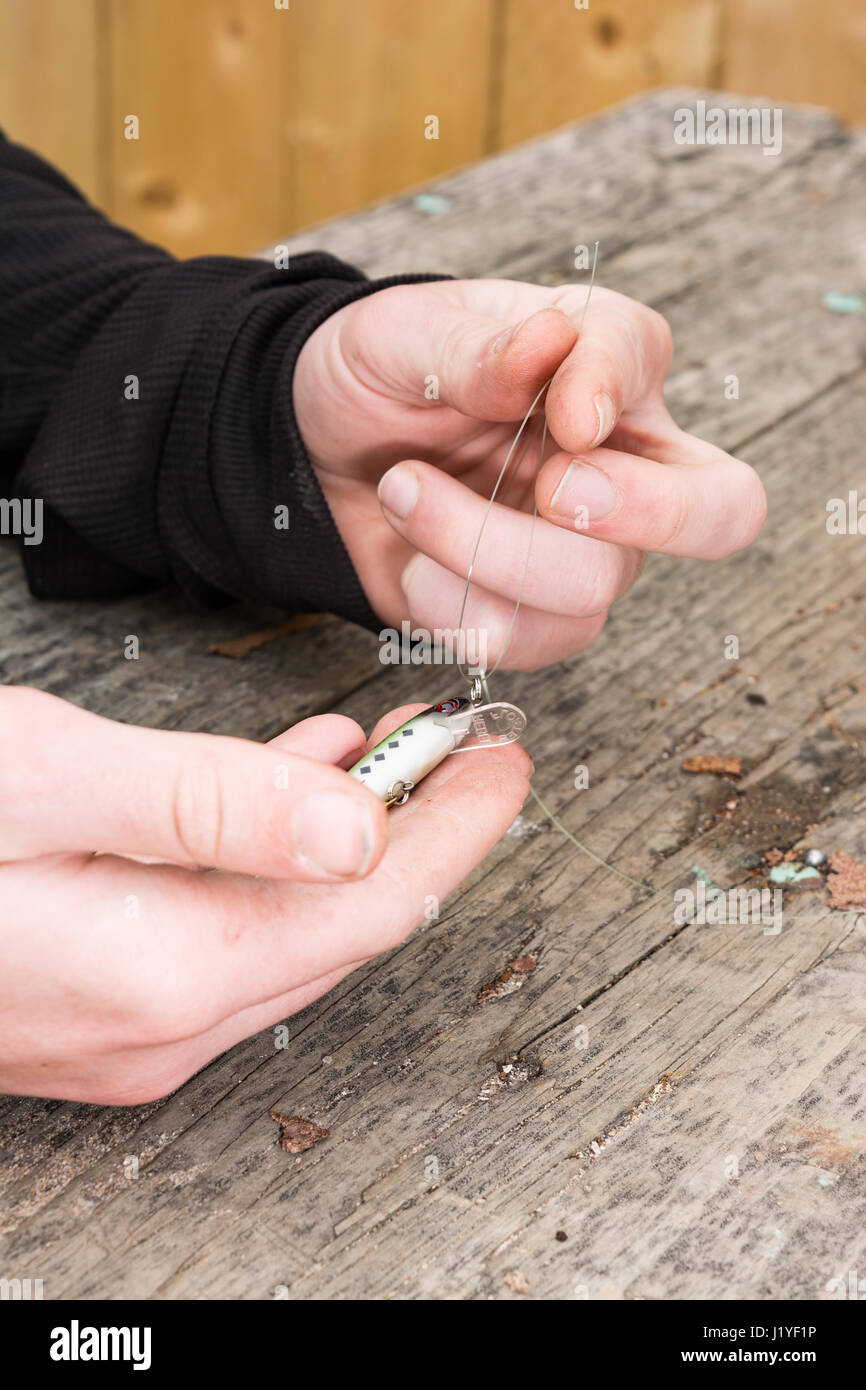 male hands tying a fishing lure to monofilament line Stock Photo Alamy
