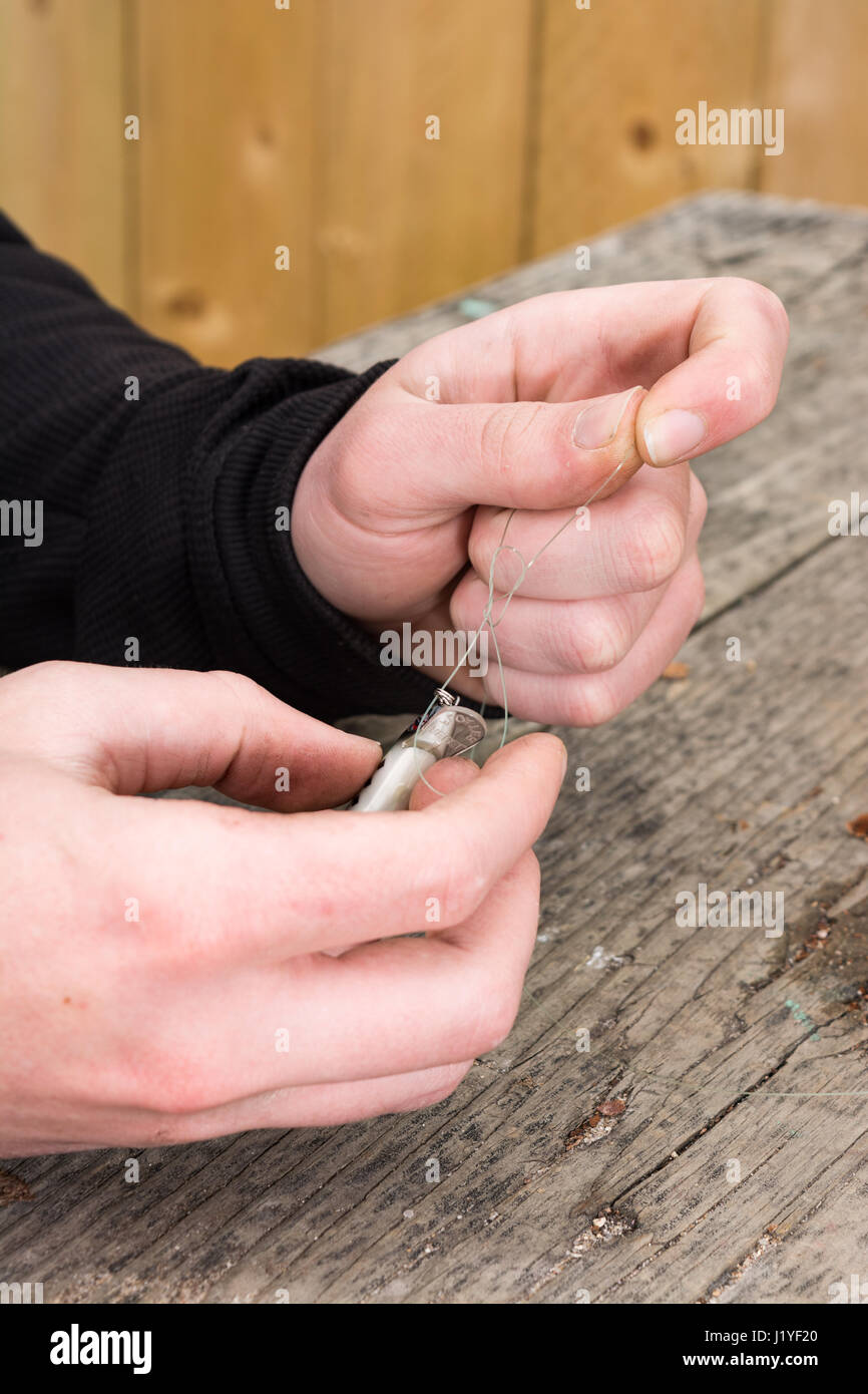 male hands tying a fishing lure to monofilament line Stock Photo Alamy
