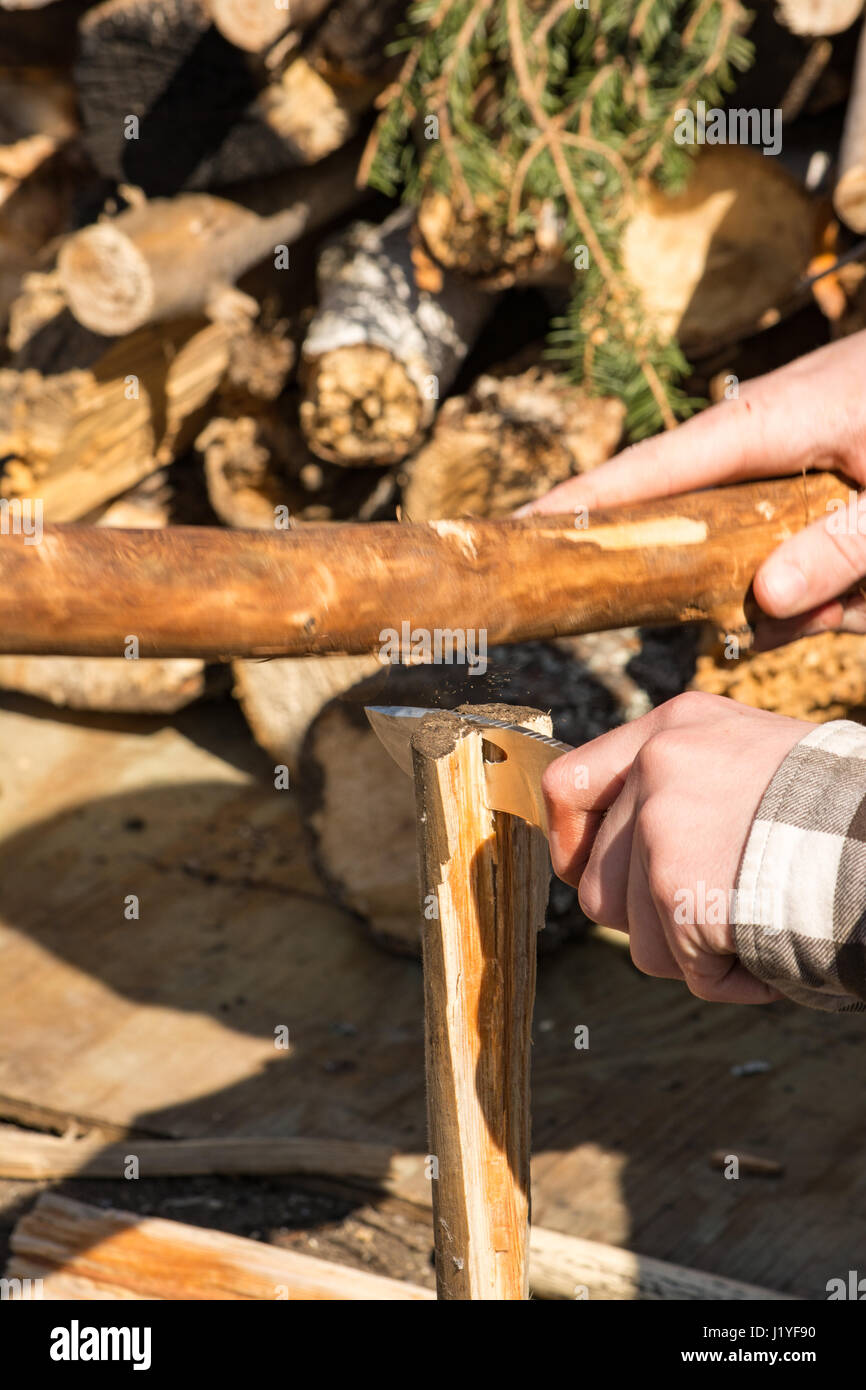 male splitting wood primitively with small log and hunting knife. Stock Photo