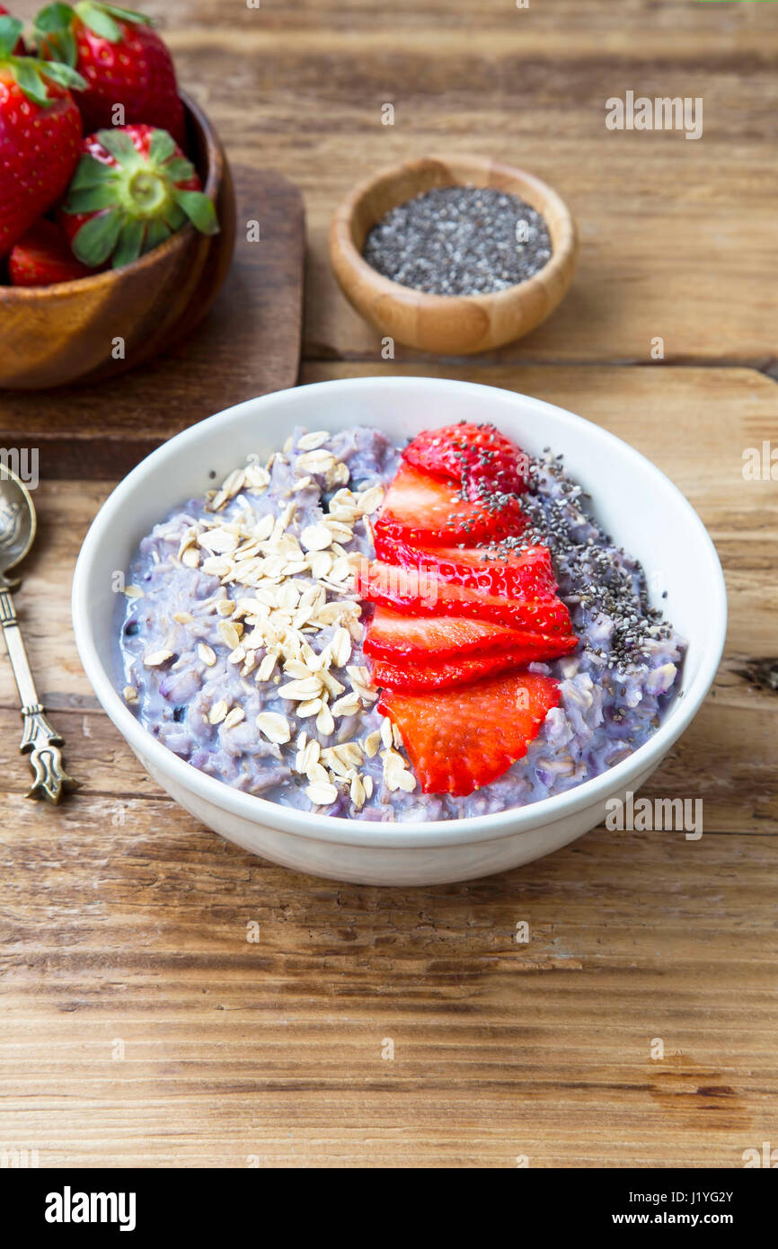 Fruits oatmeal porridge with strawberries and chia seeds in a bowl on wooden background Stock Photo