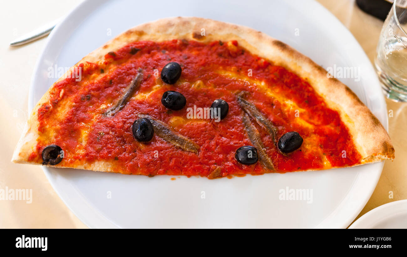 travel to Italy - above view of half of pizza with anchovies on white plate in venetian restaurant Stock Photo