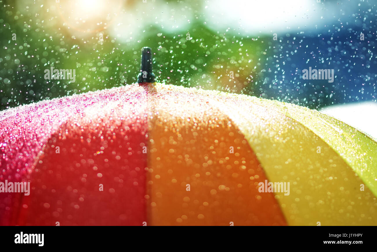 Rain drops falling onto umbella with rainbow colour Stock Photo