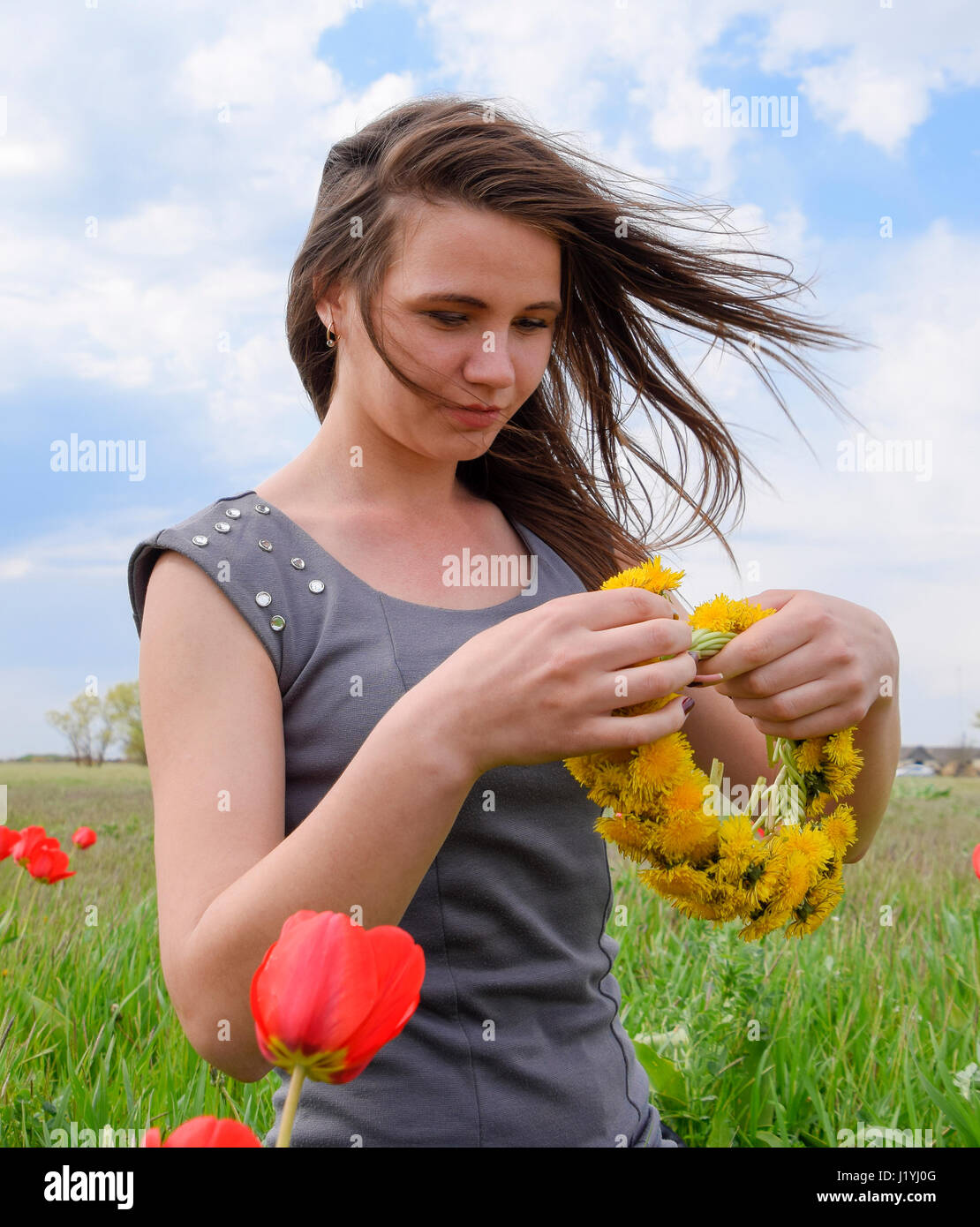 A girl with a wreath of dandelions in her hands. Beautiful fairy young ...