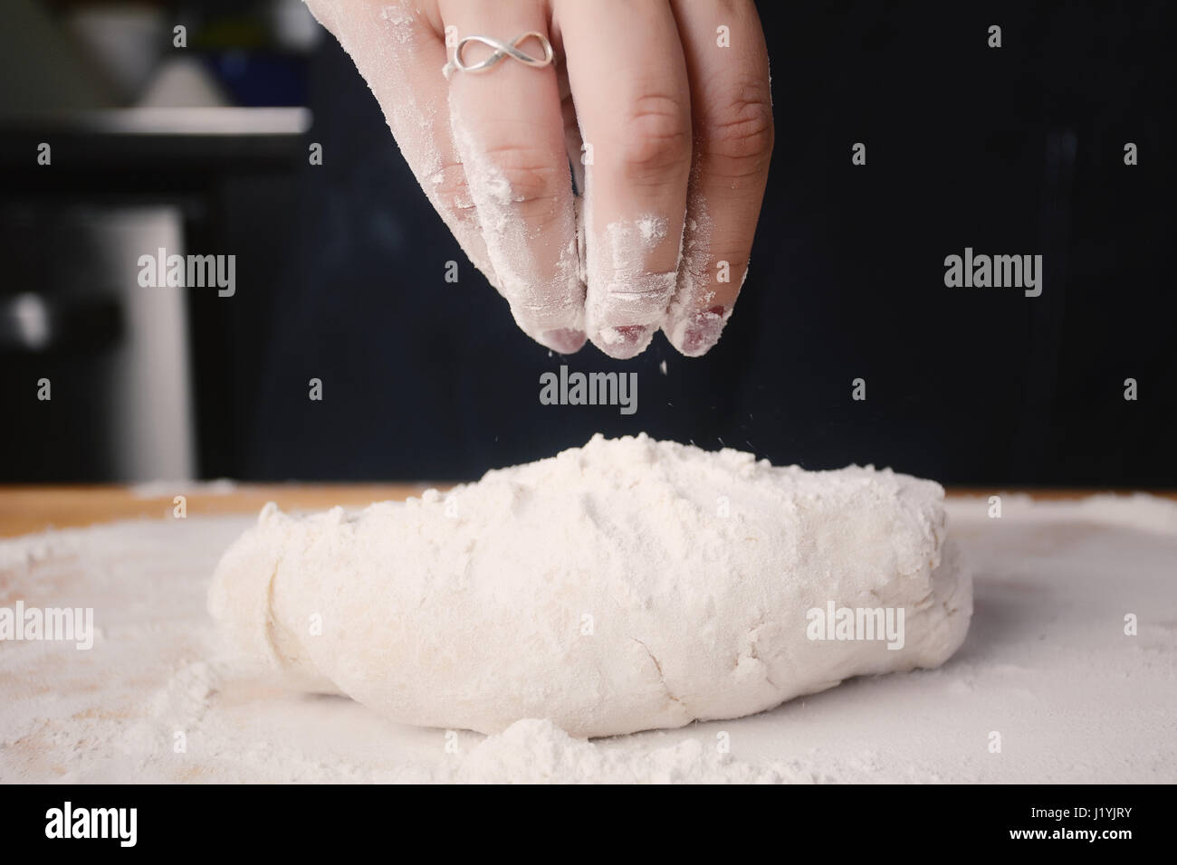 Close up of a woman hand adding flour to dough. Cooking concept Stock ...