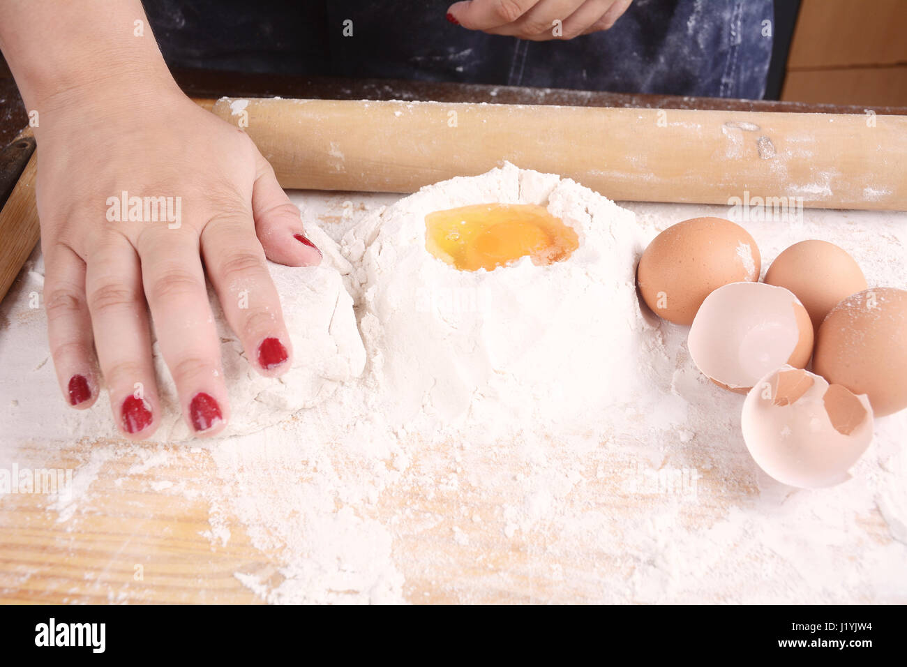 Close-up of woman hands knead dough on wooden table with flour, eggs ...