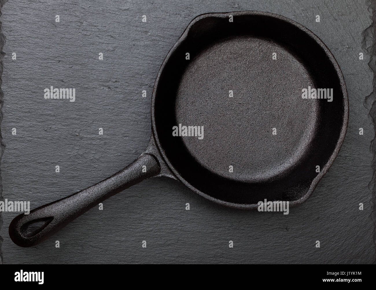 Empty cast-iron frying pan on a black slate background (top view) Stock Photo