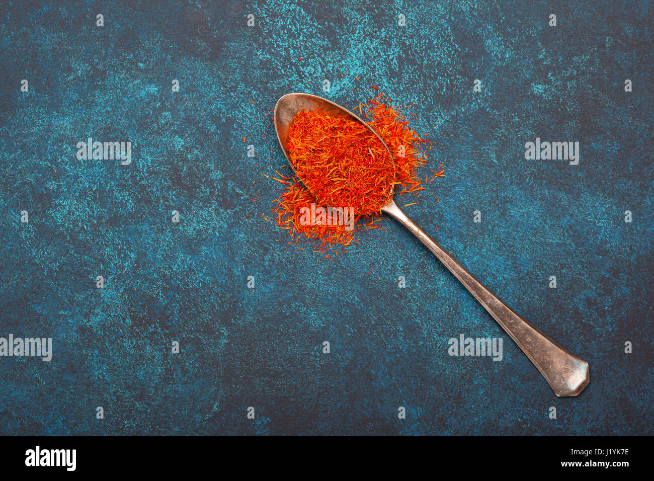Saffron in an old silver spoon on a blue background. View from above. Stock Photo