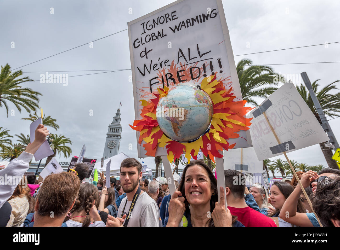 San Francisco, California, USA. 22nd April, 2017. "Ignore global warming and we're all fired!!!" reads a sign with a globe protruding in 3-D and paper flames held during the rally at Justin Herman Plaza before the San Francisco March for Science on April 22, 2017. Thousands gathered for the event  to show for support for science in the U.S. while also protesting Trump's major cuts to the Environmental Protection Agency, the National Institutes of Health and other science-related programs. A science fair was held in Civic Center Plaza after the march. Credit: Shelly Rivoli/Alamy Live News Stock Photo