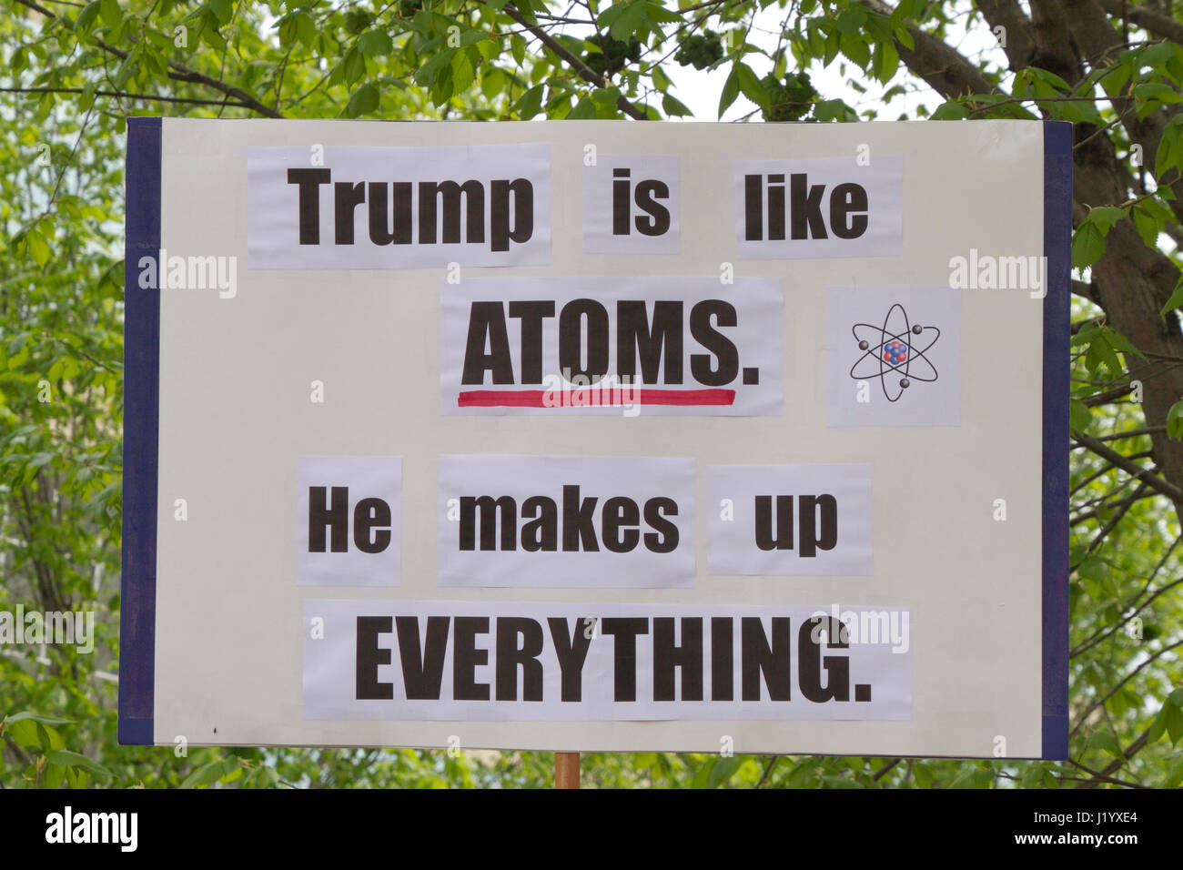 Asheville, North Carolina, USA: April 22, 2017 - Close up of a funny political sign that says 'Trump Is Like Atoms, He Makes Up EVERYTHING' displayed at the 2017 Earth Day March For Science rally protesting current Trump lies and anti-science stance. April 22, 2017 in Asheville, NC. Stock Photo