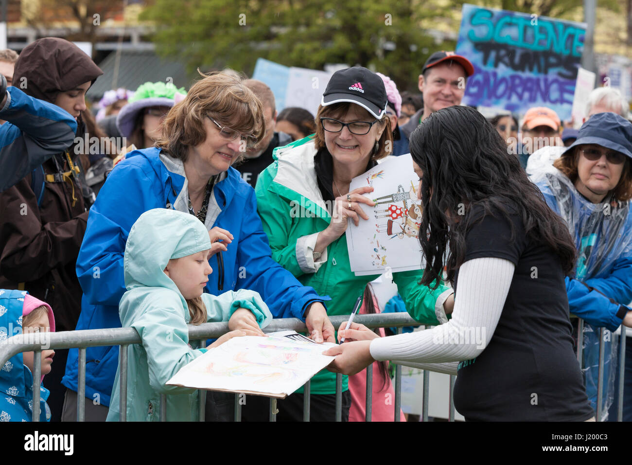 Seattle, Washington,USA. 22nd April, 2017. Speaker Tracie Delgado signs a poster for a young supporter at the rally in Cal Anderson Park. The March for Science Seattle was a non-partisan rally and sister march to the National March for Science and over 600 cities across the world on Earth Day. Thousands marched from Cal Anderson Park in the Capitol Hill neighborhood to Seattle Center to celebrate science and the role it plays in everyday lives as well as to protest the policies of the Trump administration. Stock Photo