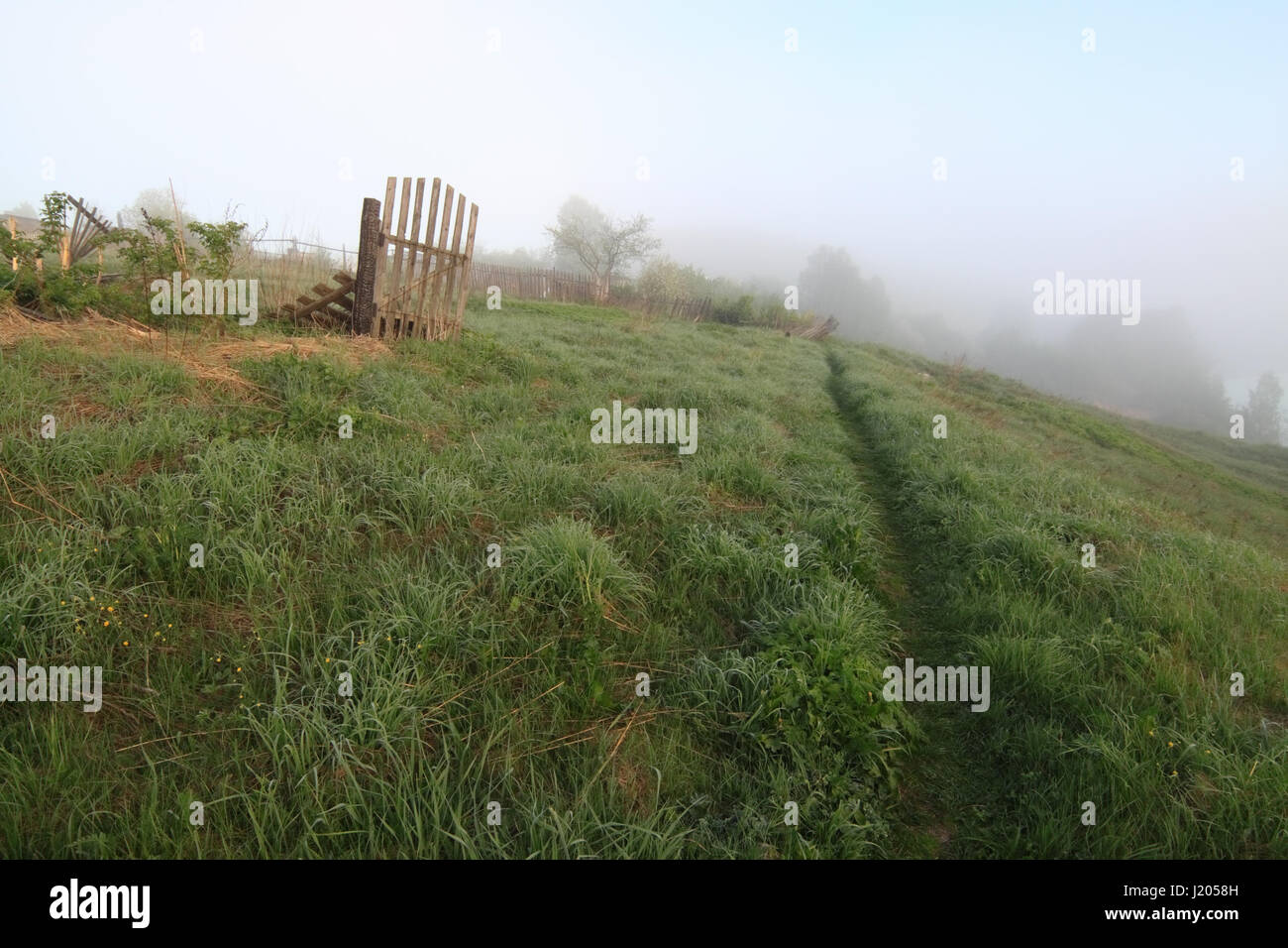 A scenic picture of rural landscape with broken wooden fence Stock Photo